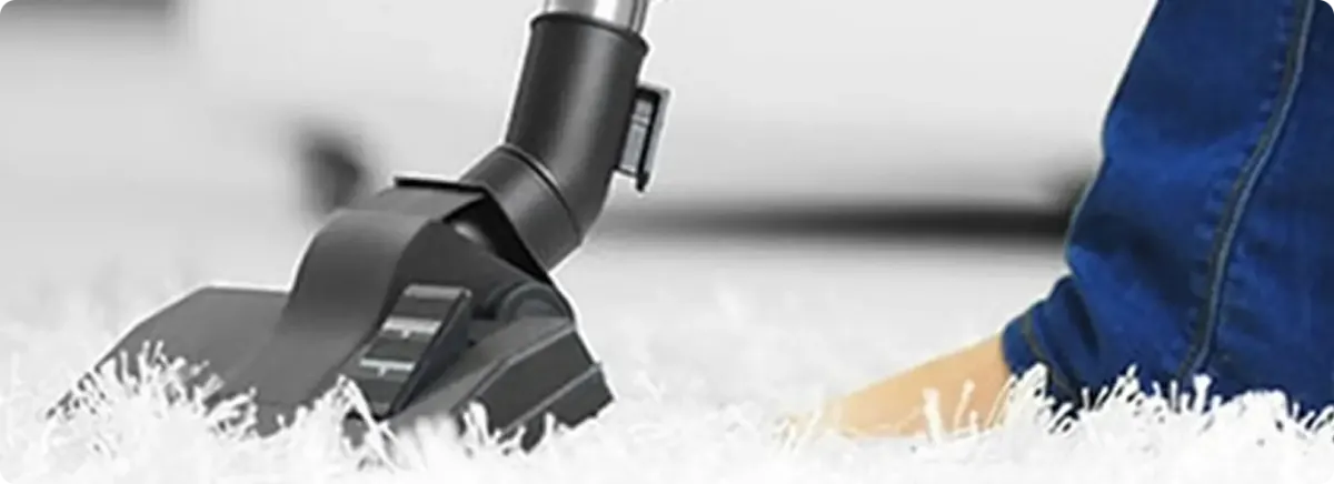 Close-up of a professional vacuuming a white carpet in Hillside.